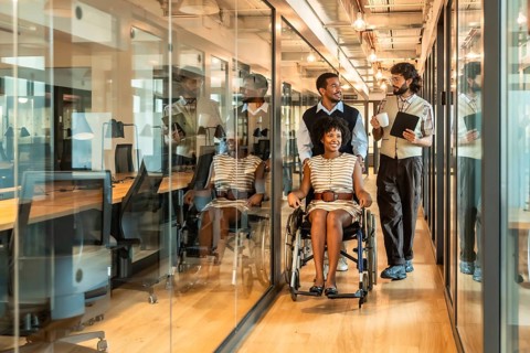 Diverse business team smiling and moving together through a contemporary glass walled office