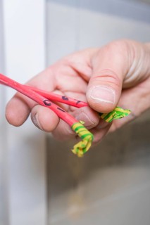 Hand holds red and green marked cable ends close to the camera