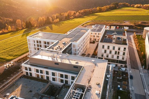 Modern buildings and nature under a glowing sunset sky, new hospital, Calw Health Campus, Black