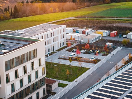 Campus with office buildings and colorful autumn trees next to a container area, new hospital, Calw