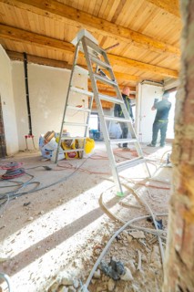 A ladder and tools on a construction site with a wooden ceiling