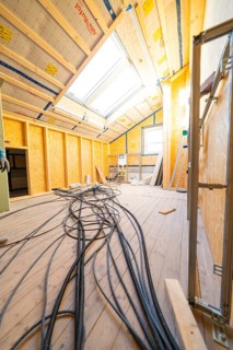 Conversion in an attic with visible wiring and incoming daylight through skylights