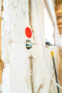 Cable and socket stick out of an unfinished wall with sketches during renovation