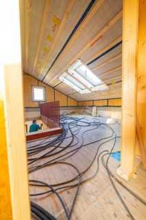 An attic under construction with wood paneling and cables