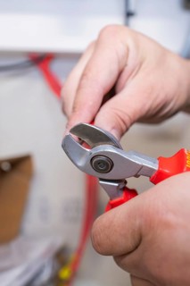 A person uses a red side cutter