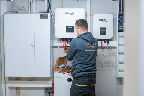Electrician works at the connection point of a solar system with inverters