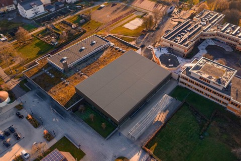 Aerial view of a modern building complex with green spaces and sun in the background, Althengstett