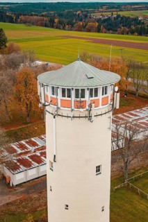 Close-up of the upper part of a water tower with green roof surrounded by autumn trees, Wasserturm,