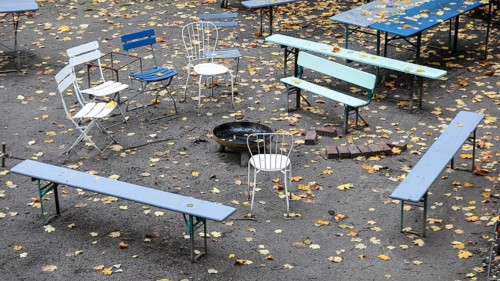 Chairs and tables stand unsorted around a fire bowl, a celebration in the garden is over, colorful