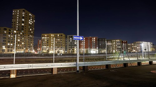 One way street on the fence, behind it a passing ICE train, illuminated apartments in a new housing