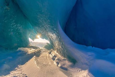 Midnight sun shining in glacial ice cave at Mohnbukta, bay at western shore of Storfjorden in