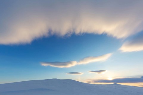 Stratus cloud rolling in over snow covered Arctic landscape at Mohnbukta, bay at western shore of