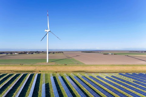 Aerial view over hybrid power plant combing solar photovoltaic modules and wind turbines, North
