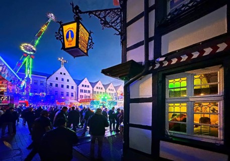 All Saints Fair in the evening with a half-timbered house and colorful illuminated rides, Old Town,