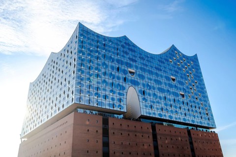 The modern Elbe Philharmonic Hall with its unique glass façade rises majestically against the blue