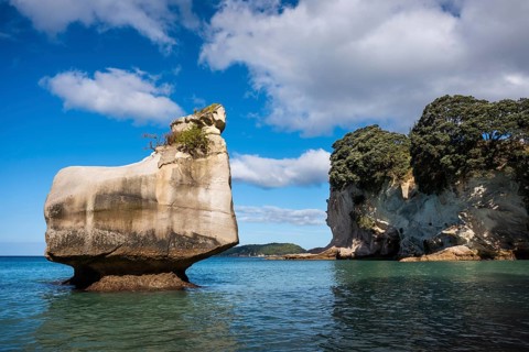 Cathedral Cove in New Zealand. Sea, sandy beach and limestone cliffs. On the left, the Smiling
