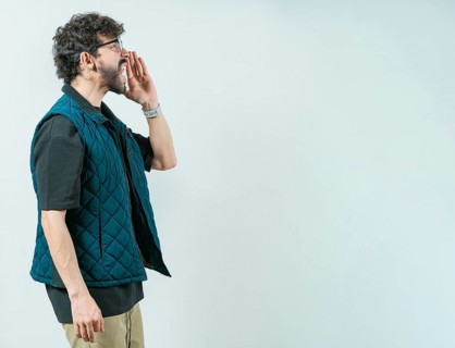 Casual young man in glasses shouting a promotion. Male person shouting an announcement isolated