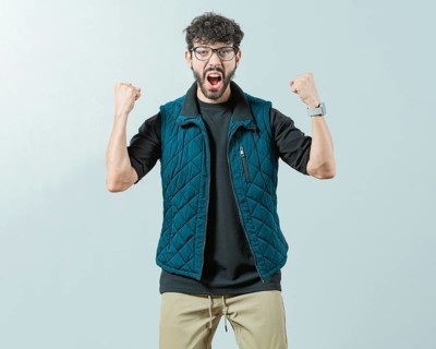 Excited young man celebrating looking at camera raising arms isolated. Happy guy with sunglass