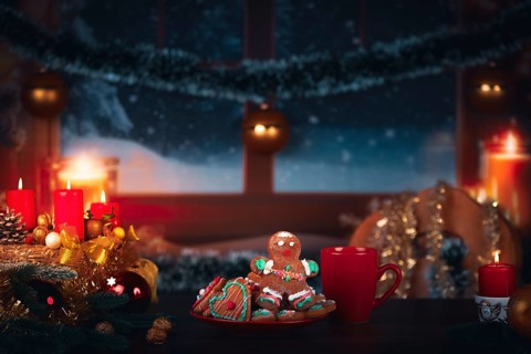 Cosy Christmas atmosphere with candles, gingerbread man and a winter view