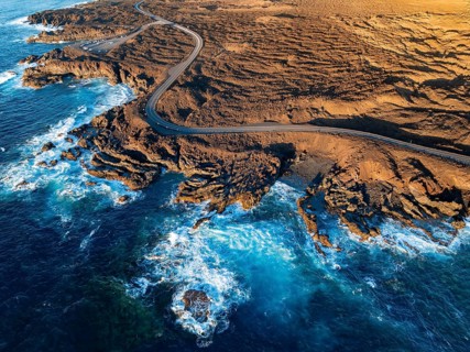 Road on the coast with lava fields, volcanic landscape near Los Hervideros, in the evening light,