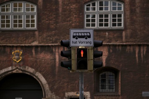 Traffic light for pedestrians, pedestrian traffic light is on red, bus traffic sign has priority,