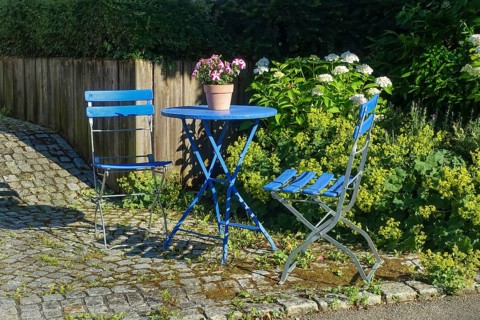 Blue garden chairs with small round table, idyll, petunias (petunia) in a plant pot, paving stones,