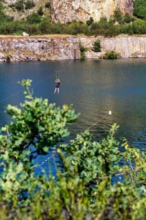 Tourist on a zip line across the lake, Opal Lake in the granite quarry, Moselleøkken
