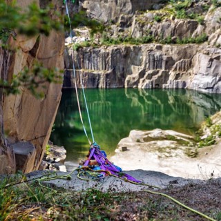 Ropes, slings and carabiners secured on a rock edge, opal lake in the granite quarry, Moselleøkken