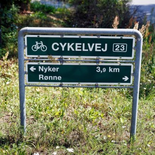 Danish sign with the inscription Radweg 23, distance to Nyker and Rønne, bicycle tour through