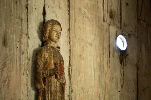 Carved wooden figure holding a book, Garmo Stave Church, Maihaugen open-air museum with houses and