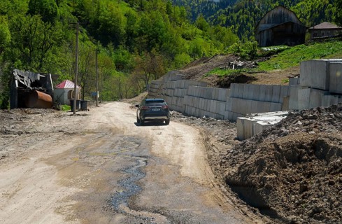 Car drives along a dirt road in a rural mountain landscape, on the way to the Goderdzi Pass near