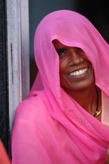 Smiling woman, face partly covered by long, scarf-like pink shawl or Dupatta, also known as Chunni,