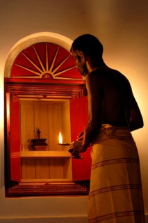 A man prays in front of a small shrine with a burning flame, spiritual atmosphere in warm light,