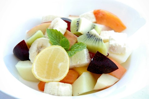 Fresh fruit salad with lemon, banana, papaya, kiwi, plums, melon and mint leaves in a bowl, Palace