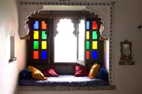 Cosy sitting area with colorful window and pillows, traditional style and cozy atmosphere,