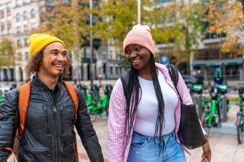 Diverse happy young adult friends are enjoying a cheerful walk together on a city street, smiling