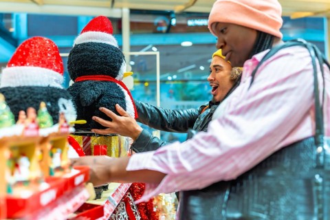 Diverse couple browsing holiday decorations in a store, a man looking surprised and excited while