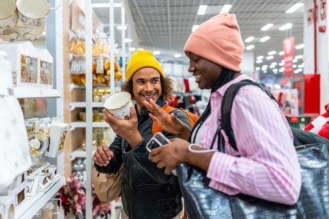 Happy couple smiling and browsing home decor in a modern store, examining a decorative item while