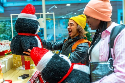 Young diverse couple excited discovering festive penguin decorations while shopping for holiday