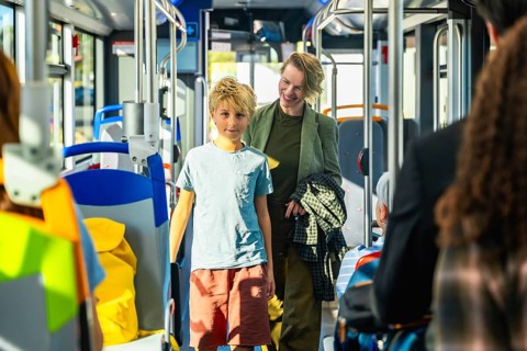 Mother and son traveling together inside a modern public transport bus, enjoying a casual family
