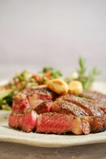 Juicy grilled steak medium rare on a white plate, with tender pink meat visible