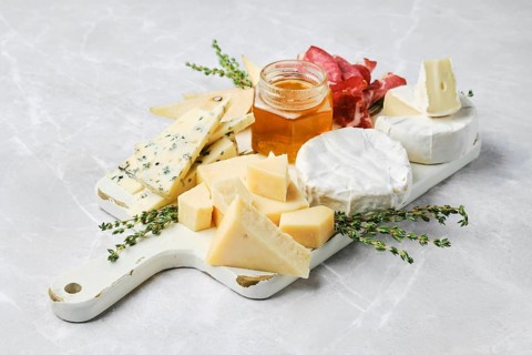 A beautiful spread featuring various types of cheese, honey in a jar, and slices of cured meat on a