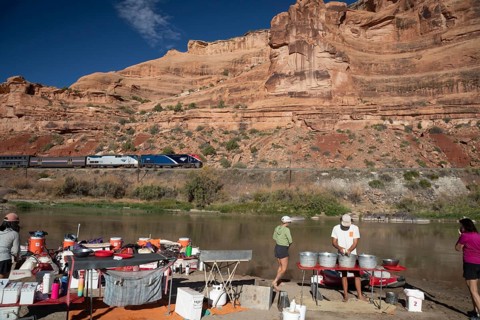 Loma, Colorado - Amtrak's California Zephyr passes a river rafters' campsite on the Colorado River