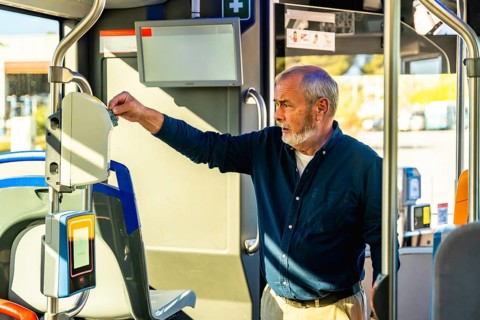 Senior man inserting his travel ticket into a modern validator device inside a public