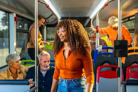 Diverse group of passengers on a clean modern city bus, smiling and commuting together seated and
