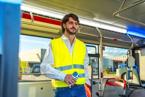 Man wearing an unbuttoned white shirt, blue jeans, and a yellow reflective safety vest, holding a