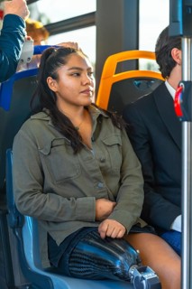 Young woman with a carbon fiber prosthetic leg sitting on public transport, riding a modern bus,
