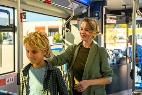Mother and son share a warm moment on a modern city bus, woman resting her hand on his shoulder as