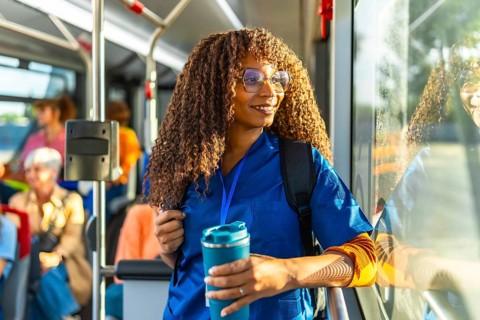 Young black woman nurse wearing blue scrubs and carrying a backpack, happily commuting to work on a