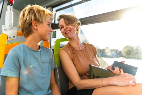 Happy mother and son enjoying a conversation while sharing a seat on a public transport bus, with